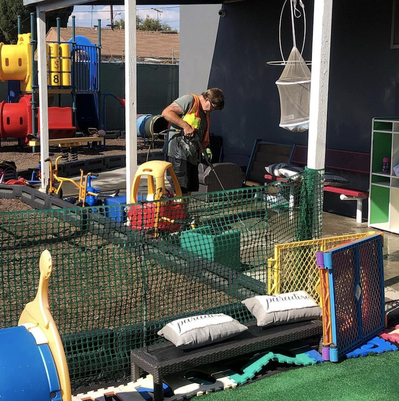 A construction worker is fixing the concrete at The Learning Box playground to be safe and clean.