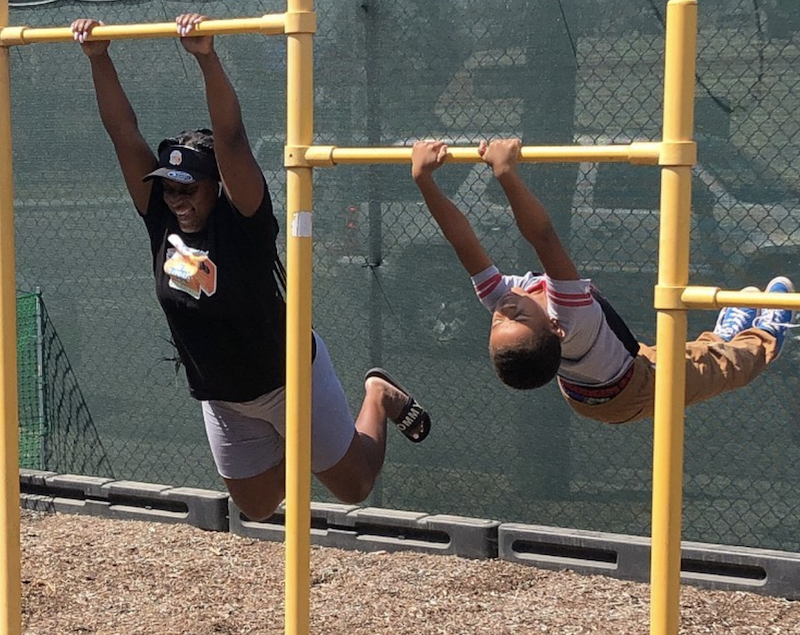 Teacher and child are swinging on the jungle gym.